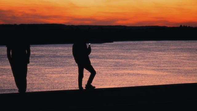 At the riverside at twilight, people enjoy a peaceful evening