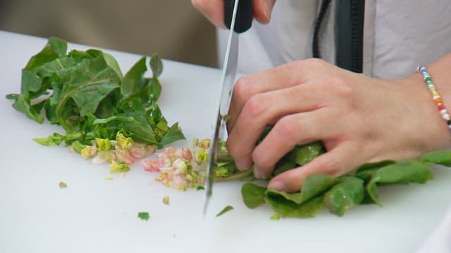 Cutting spinach with a knife on a cutting board