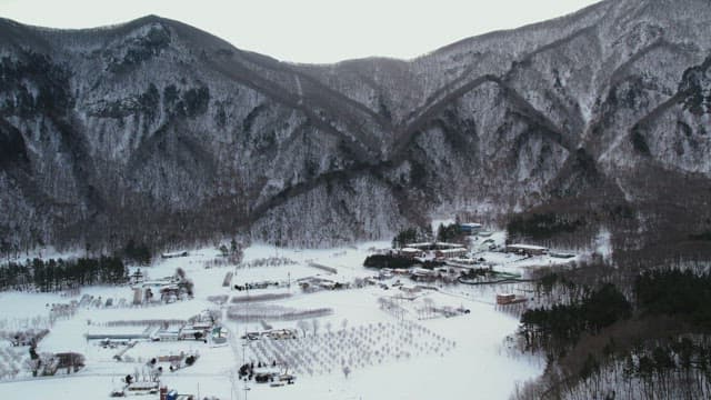 Snow-Covered Village Under Lush Snowy Mountains