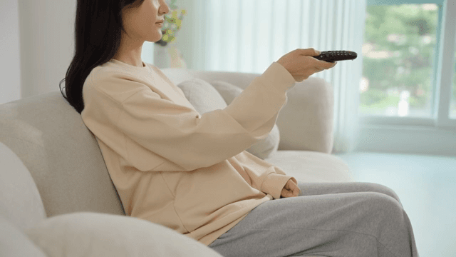 Woman operating a remote control on the sofa
