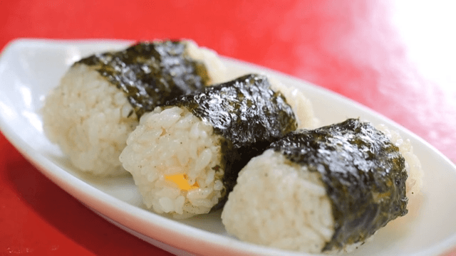 Rice balls with cheese and seaweed on a red table
