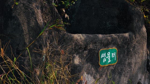Green name tag for an old spring water site made of rock