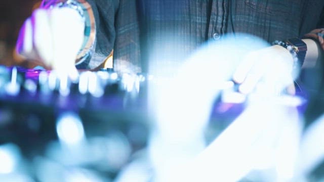 DJ's Hands Adjusting the Volume on the Audio Mixer