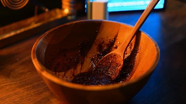 Adding white rice cakes to a wooden bowl with seasoning