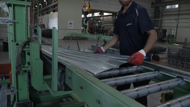 Worker handling metal sheets in a factory