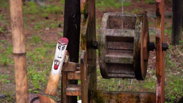Outdoor wooden waterwheel with face carving
