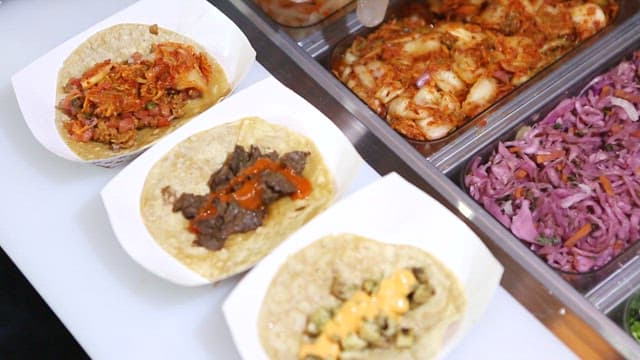 Preparing tacos with kimchi and various ingredients on the kitchen counter