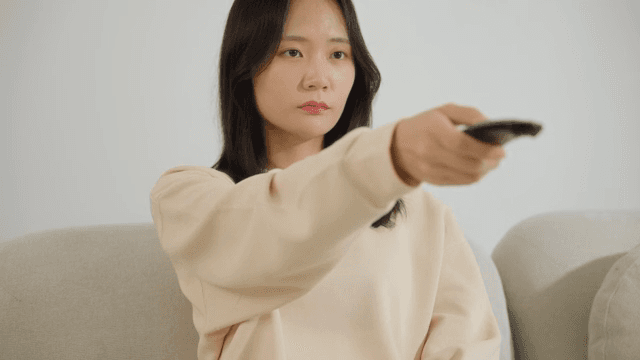 Woman operating a remote control on the sofa