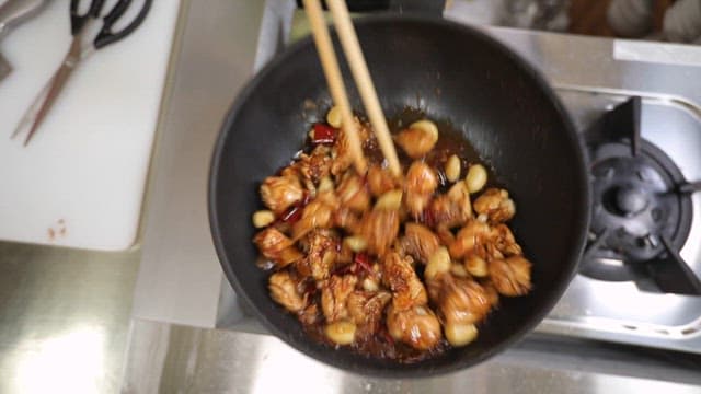 Cooking chicken with garlic and chili peppers on a stove
