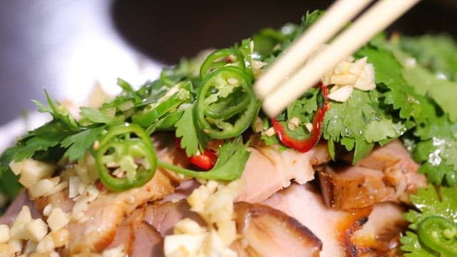 Five-spice pork garnished with herbs and peppers