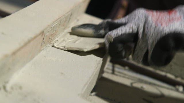 Worker sanding a concrete surface with his gloved hands