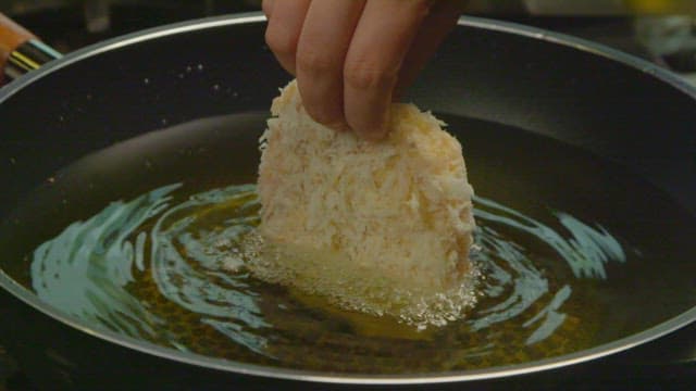 Placing a breaded pork cutlet in hot oil