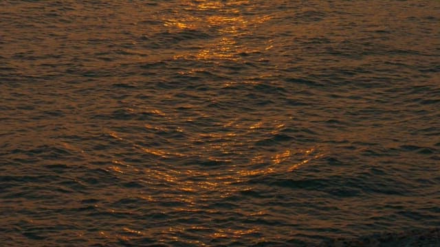 Sunset over the calm ocean near a seaside lighthouse