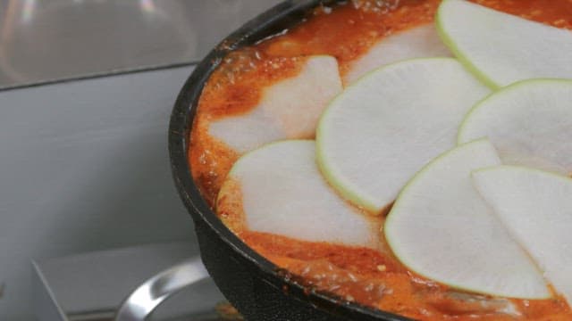 Boiling pot of spicy stew with radish slices on top