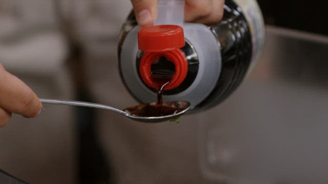Adding soy sauce to vegetables being stir-fried in a frying pan