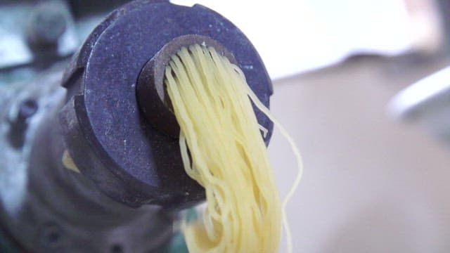Fresh noodles being extruded from a machine