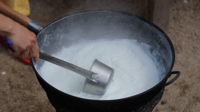 Stirring milk in a large pot outdoors