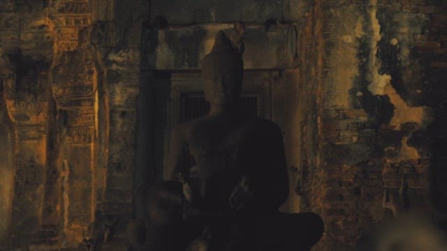 Monkeys playing around an ancient Buddha statue at dusk