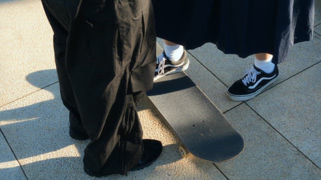 Man who helps a woman skateboard