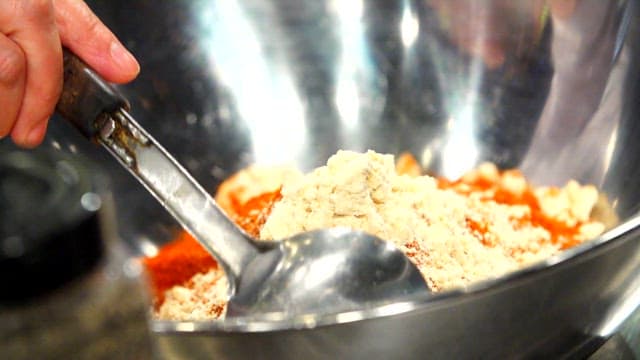 Mixing ramen and red pepper powder in a metal bowl