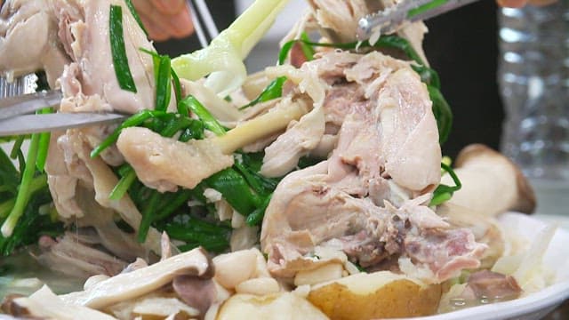 Leg of a native chicken being lifted with tongs