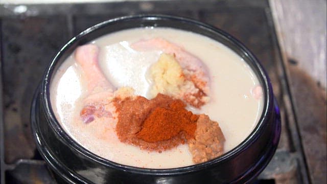 Duck soup mixed with seasoning with a ladle