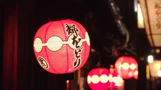 Bright red lanterns hanging in the evening streets of a bustling city
