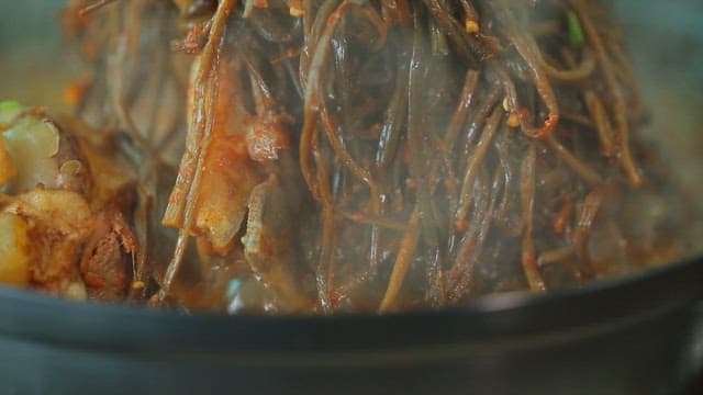 Plate of pork backbone stew topped with sweet potato stem salad