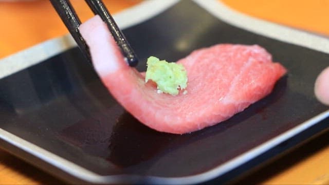 Lifting Tuna Sashimi Topped with Wasabi Using Chopsticks
