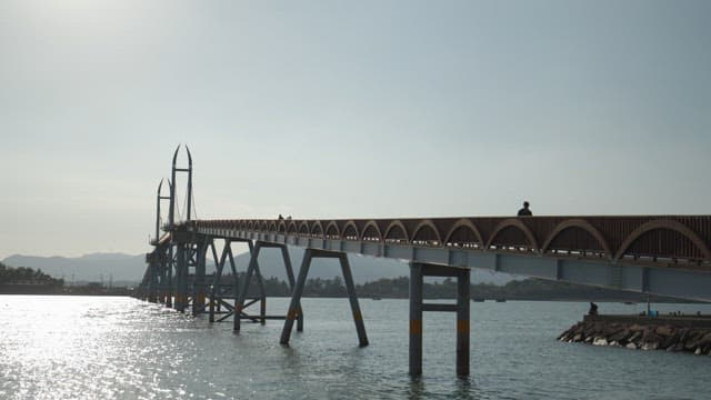 People walking across a scenic sunny bridge