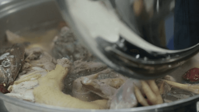 Pot of boiling samgyetang made with abalone being uncovered