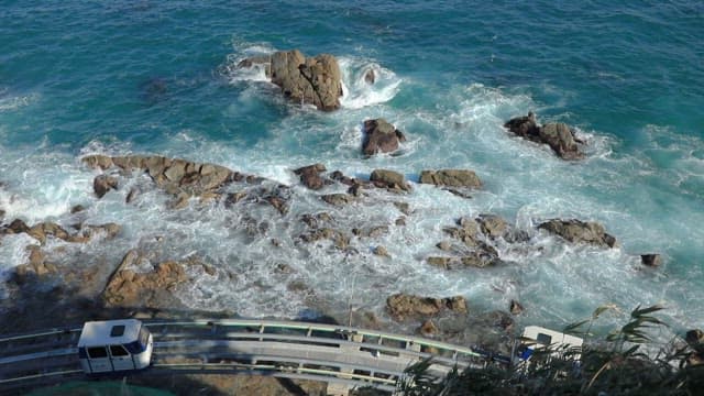 Coastal Monorail above the Rocky Shoreline with Waves on a Clear Day