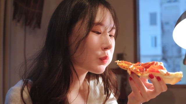 Woman enjoying a slice of pizza indoors