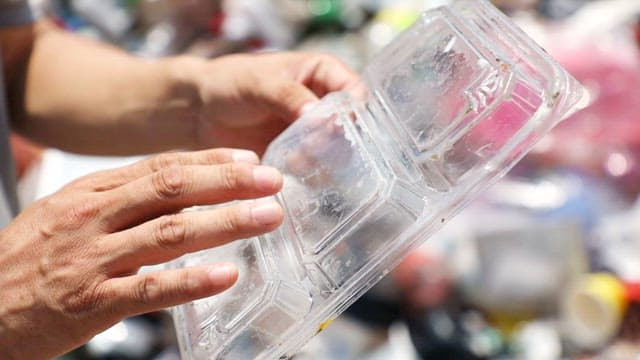 Hand holding a contaminated plastic container
