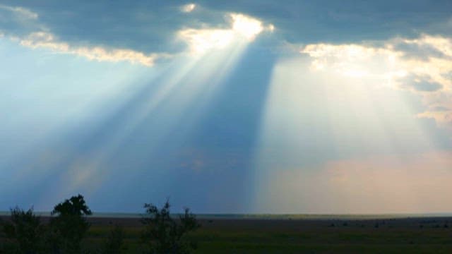 Sunlight Beaming Through Clouds Over Plains
