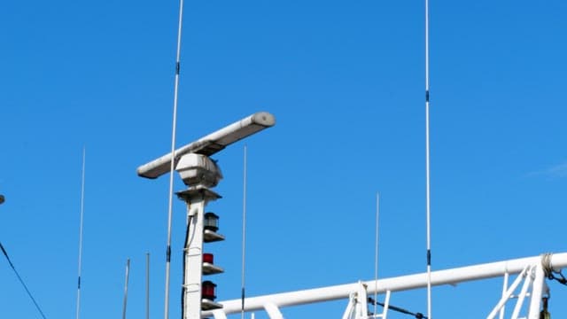 Radar tower and antennas on a ship under a clear blue sky
