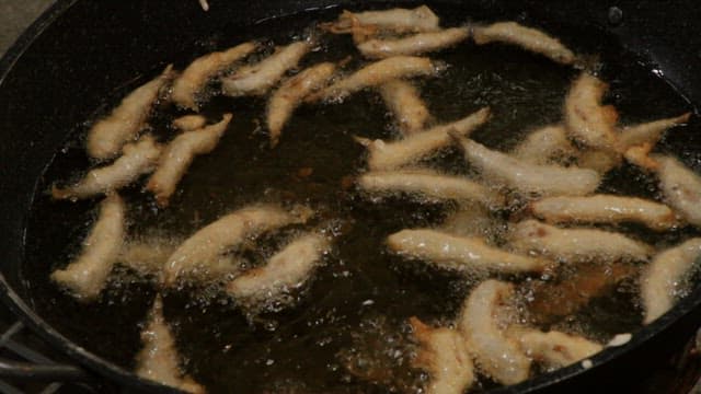 Fried anchovies cooked in hot oil in a frying pan
