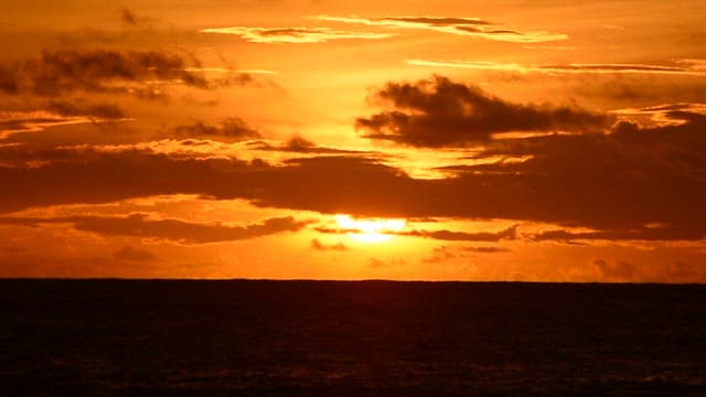 Sunset over the ocean with vibrant orange sky