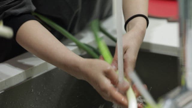Washing green onions under running water
