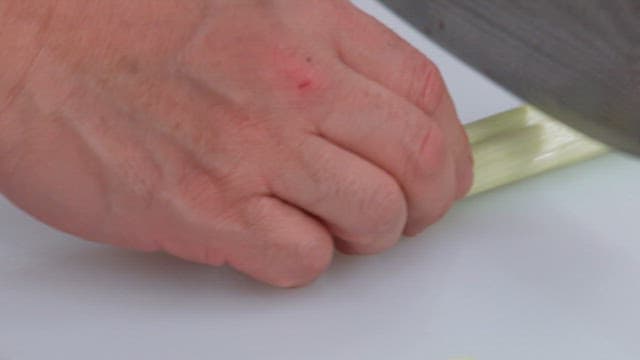 Chopping green onions with knife on a cutting board