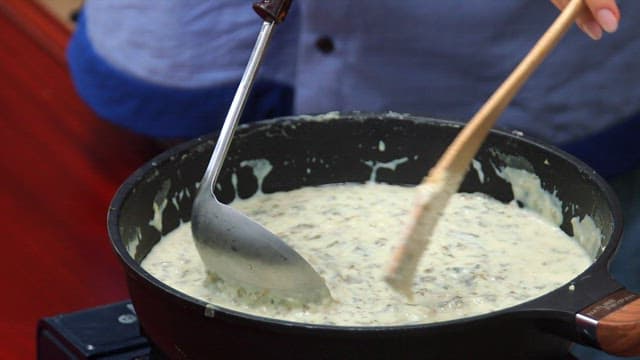Ladleful of warm soup with dried radish greens into a bowl