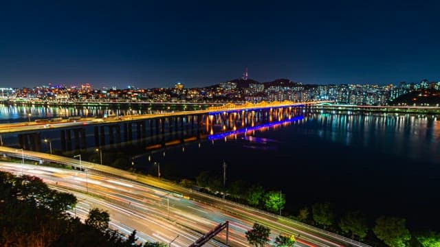 Illuminated Riverside Cityscape and Bridge at Night