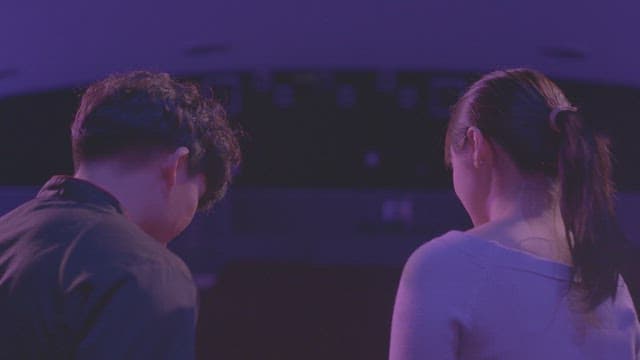 Back view of lovers sitting under purple lights