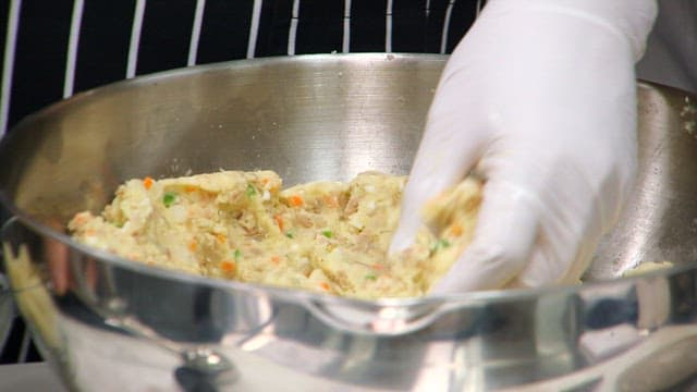 Mixing ingredients for croquette in a metal bowl