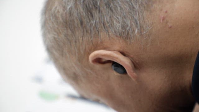 Side view of an elderly man wearing wireless earphones