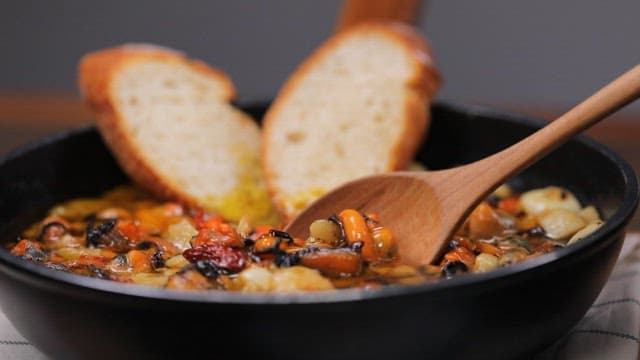 Slice of bread topped with mussels gambas in a pan