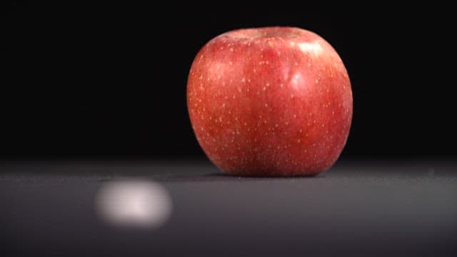 Single Red Apple and Nutritional Supplements on a Dark Background