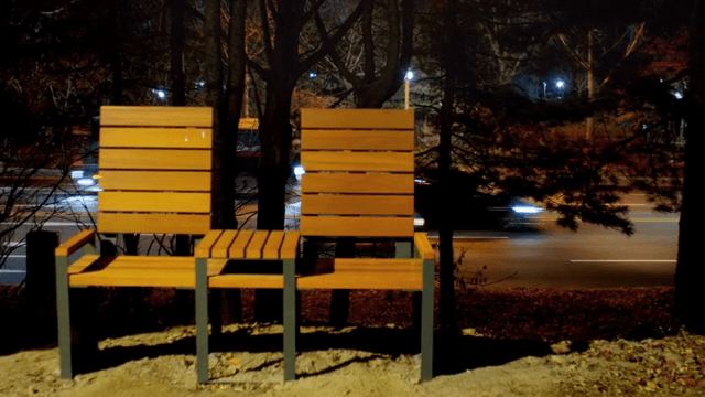 Wooden benches by a road at night