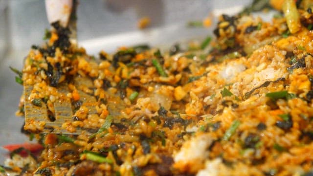 Korean griddled fried rice being mixed with vegetables