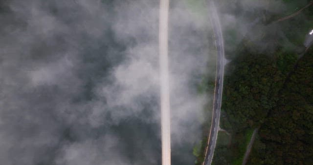 Road cutting through a misty forest